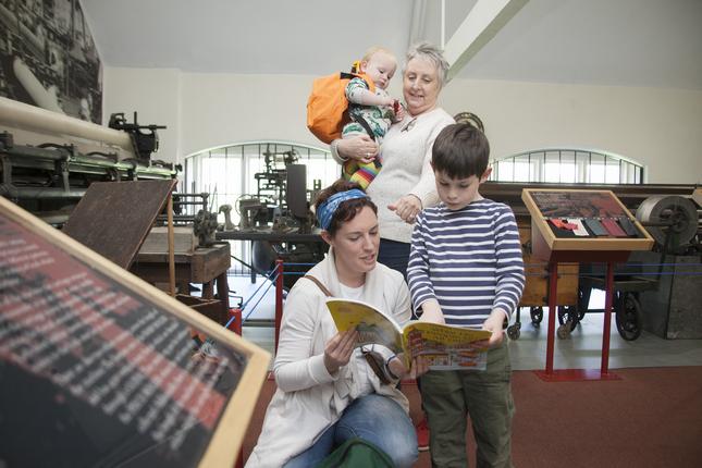 Two women, a boy and a baby looking at a book