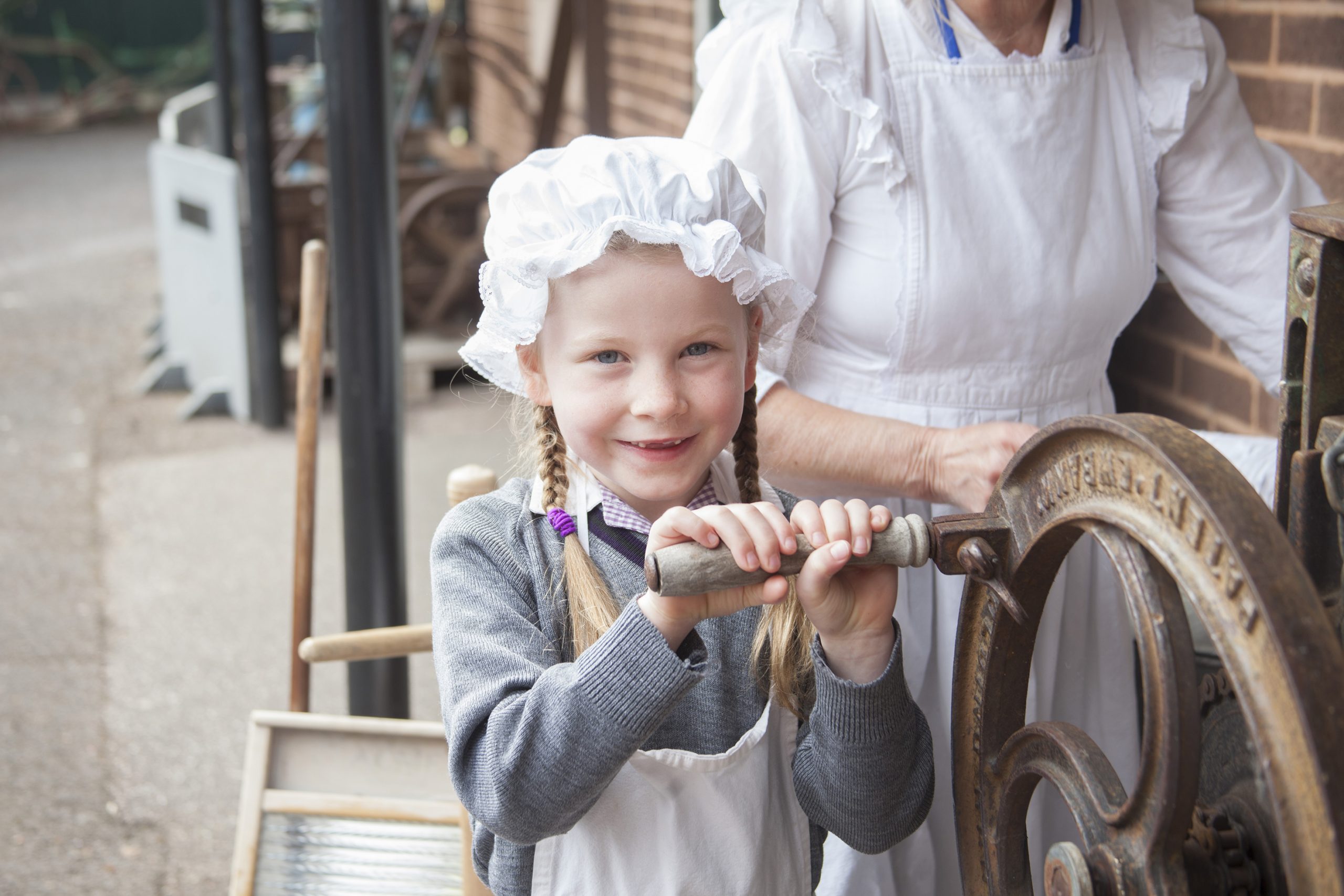 A girl turning the handle of a mangle