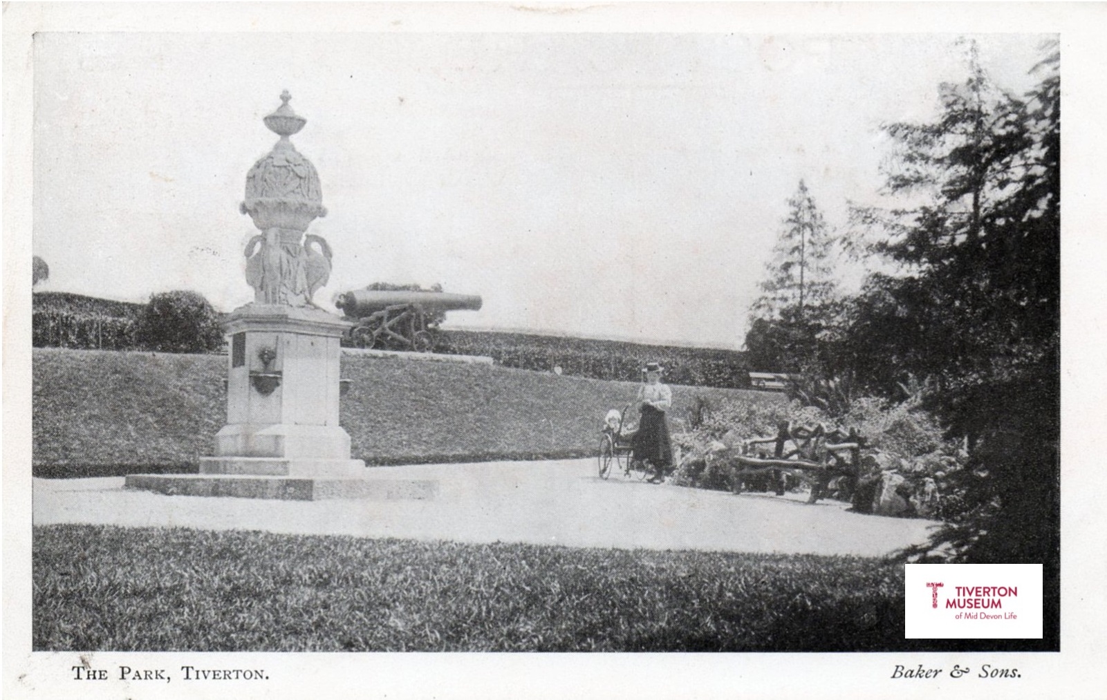 A large ornamental drinking fountain in a park with people in Edwardian dress.