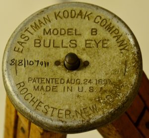 Base plate of a tripod; a worn metal disc with information about the manufacturer, Eastman Kodak Company