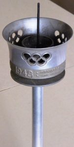 Olympic torch with the Olympic symbol of five intertwined rings cut out of the bowl and '1948' in relief