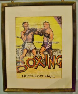 A framed poster showing an illustration of two men boxing. Writing underneath the scene says 'BOXING Heathcoat Hall'