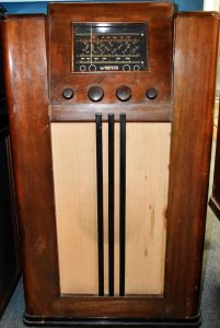 An old radio - a large, tall wooden box with with dials and a display showing frequencies