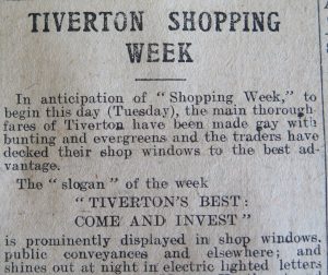 A photo showing a close up of an article in a newspaper about 'Tiverton Shopping Week'. Black type on white paper. 