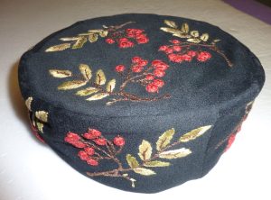 Smoking cap of a soft looking navy material embroidered with red berries and green leaves.