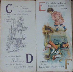 Two pages of a book which appears to be for learning the alphabet. The letters featured on the pages visible are C, D, E and F. These letters are in large bold font in front of a relevant verse for each letter. The verses are accompanied by illustrations which match the verse. The left hand page reads 'C is for Clarissa for whom Carrie's making A most charming Chain, the greatest care taking. D is for Dear Dolly who sits still and gazes, And D for Delight and D for the Daisies.' The accompanying illustration is of a little girl wearing a pinafore dress and bonnet making a daisy chain, while a doll sits still at her feet. The right hand page reads 'E stands for the Engine that's had a great smash, F stands for the Fender and Freddy so rash.' The illustration accompanying this verse is of a little boy walking away from a toy steam engine that lying on it's the floor in front of a coal fire with its 'passengers' (dolls and toy soldiers) strewn across the floor.