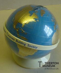 A money box in the shape of a globe. It is blue with the shape of the countries in gold