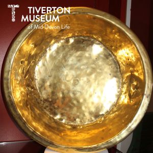 A close up of the inside of a very shiny brass dish. There are dents all around it showing it was presumably well used.