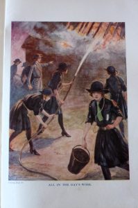 An illustration from the 'Golden Annual for Girls'. The illustration has a title below it: 'All in a Day's Work'. Several young women are pictured wearing uniforms with skirts and low heeled shoes, tackling a blazing fire. One carries a bucket while several others are using a hose to take on the fire.
